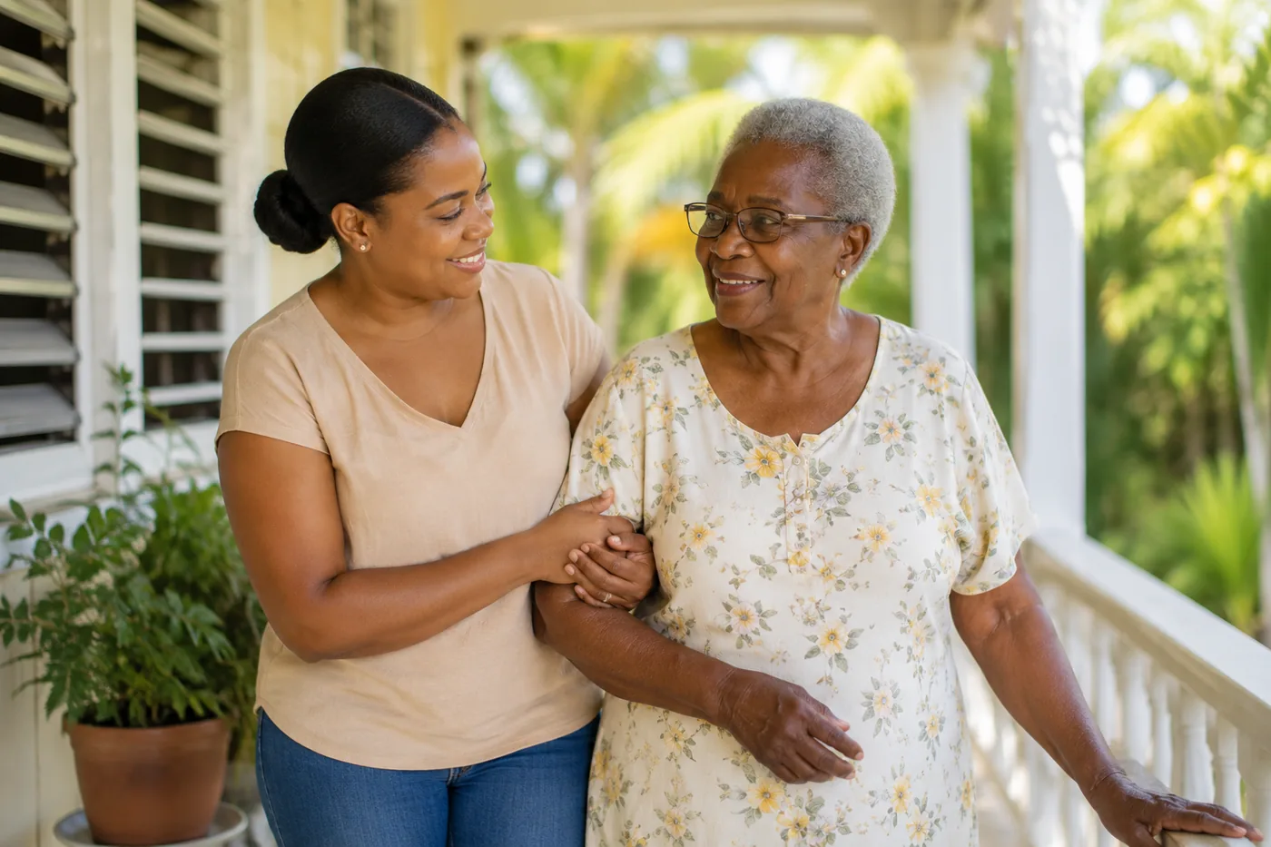 A caregiver walking arm-in-arm with an elderly Jamaican woman on a sunny veranda — illustrative.
